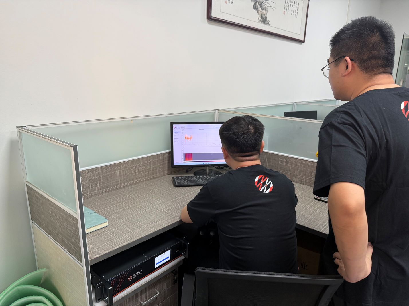 Planck Sensing team reviewing temperature data with the DTS instrument installed below the desk
